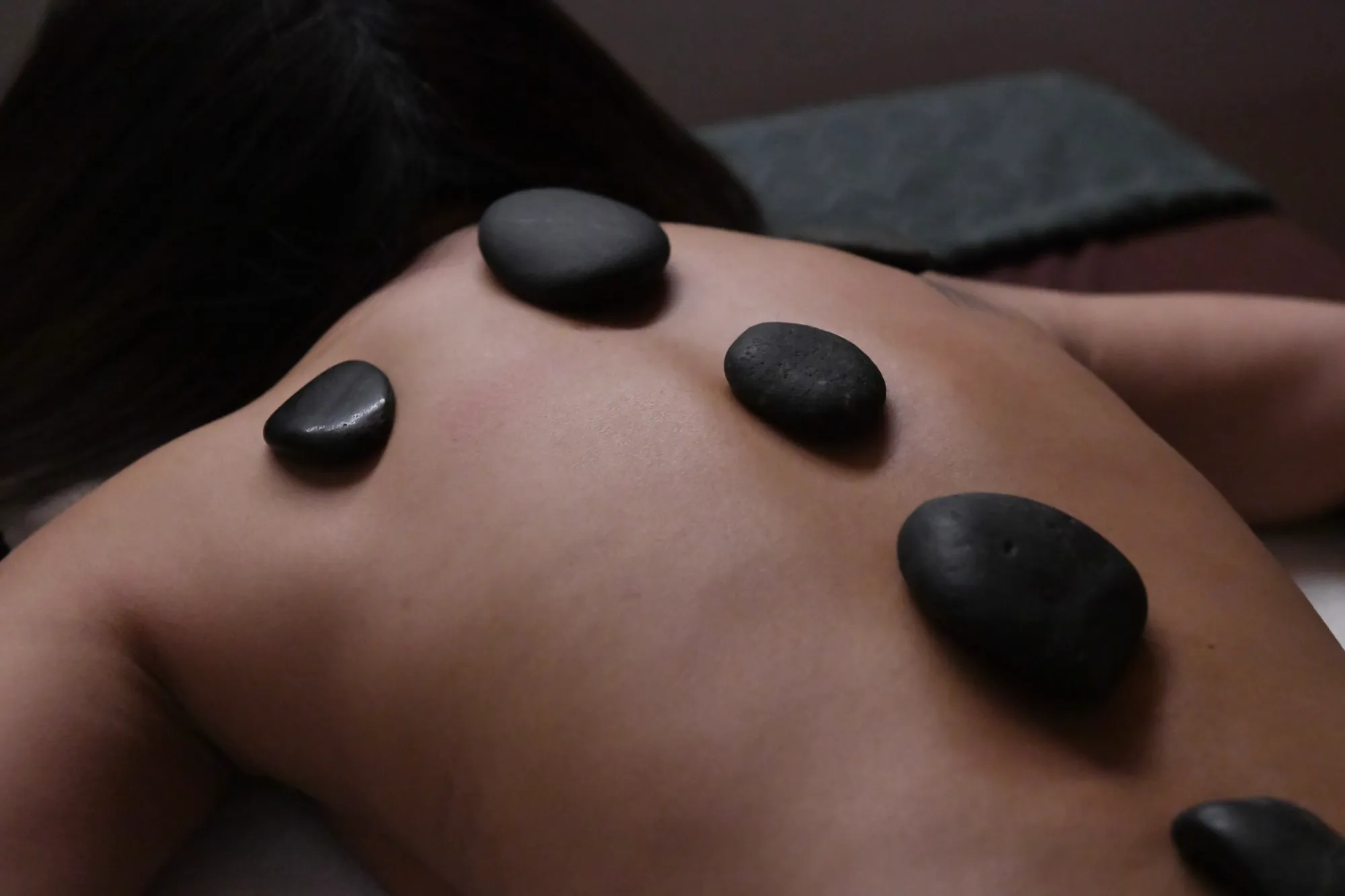 Woman laying down on massage table during a hot stone thai massage
